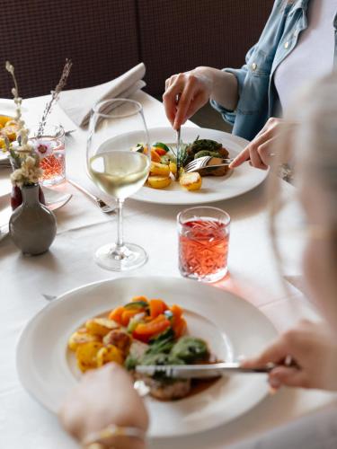 a table with two plates of food and glasses of wine at Panorama Hotel Flora in Villandro