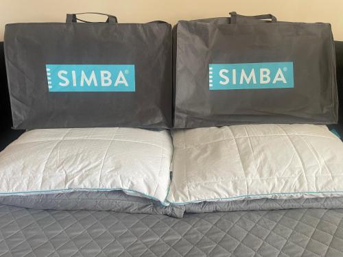 two white pillows on a bed with bags on them at Leamington Loft in Leamington Spa