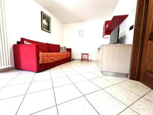 a living room with a red couch on a tiled floor at Borgo antico con terrazzo panoramico - Bluchalet in Aosta