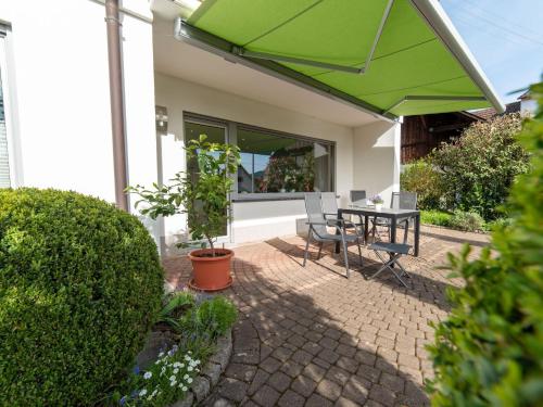 a patio with a green umbrella and a table and chairs at Ferienwohnung Pusteblume in Kappelrodeck