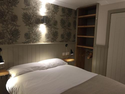 a bedroom with a bed with white sheets and wallpaper at The Harbour Guest House in Irvine