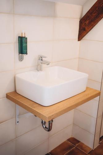 a white sink on a wooden shelf in a bathroom at Penzion Tlustá kachna in Chrudim