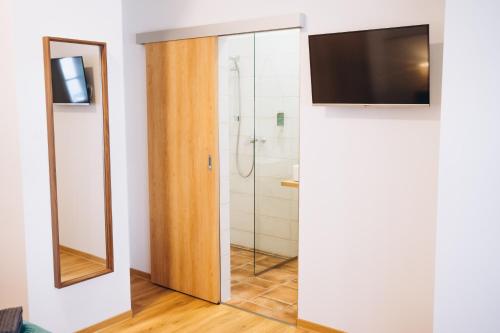 a bathroom with a shower and a television on a wall at Penzion Tlustá kachna in Chrudim
