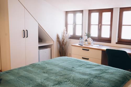 a bedroom with a bed and a desk and windows at Penzion Tlustá kachna in Chrudim