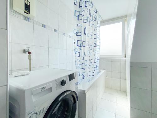a white washing machine in a white tiled bathroom at City Appartement in Gelsenkirchen