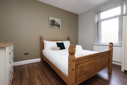 a bedroom with a wooden bed and a window at Modern Comfort 4 Bedrooms and Great Location in Cardiff
