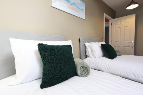 two beds with green and white pillows in a room at Modern Comfort 4 Bedrooms and Great Location in Cardiff