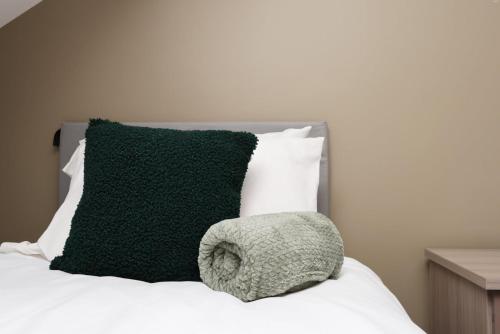 a green pillow sitting on top of a bed at Modern Comfort 4 Bedrooms and Great Location in Cardiff