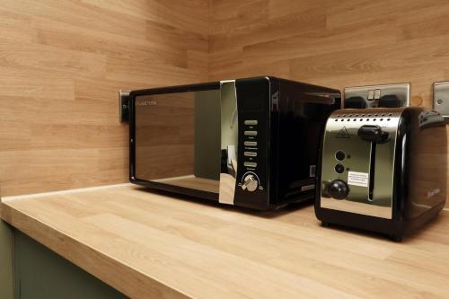 a black microwave and a toaster oven on a counter at Modern Comfort 4 Bedrooms and Great Location in Cardiff