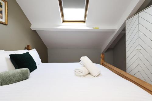 a bedroom with a white bed with a skylight at Modern Comfort 4 Bedrooms and Great Location in Cardiff