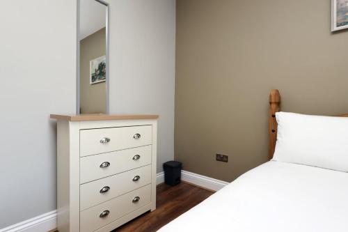 a bedroom with a bed and a dresser with a mirror at Modern Comfort 4 Bedrooms and Great Location in Cardiff