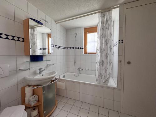 y baño blanco con lavabo, bañera y lavamanos. en Chalet Luise 3, en Wengen