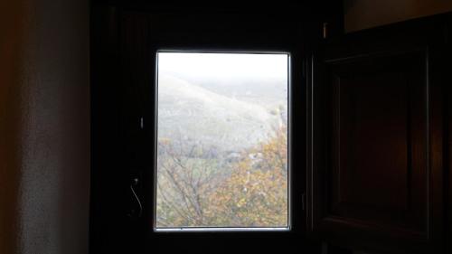 a window in a room with a view of trees at Festina Lente - Guest House in Santo Stefano di Sessanio
