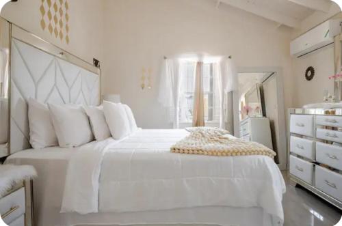 a white bedroom with a large white bed and a mirror at Barefoot Bliss Short Term Rental with pool in Colbeck Manor in Claremont