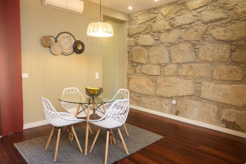 a dining room with a table and chairs and a stone wall at Oporto Yellow Villas in Porto