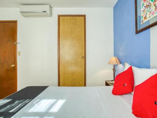 a bedroom with a bed with red pillows at Capital O Parador Crespo Hotel, Oaxaca in Oaxaca City