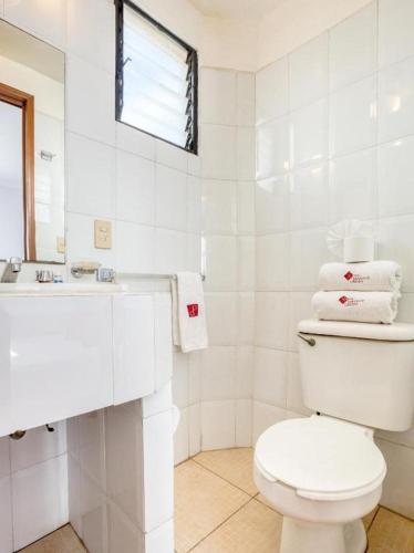 a white bathroom with a toilet and a sink at Capital O Parador Crespo Hotel, Oaxaca in Oaxaca City