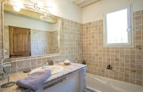 une salle de bain avec un lavabo, une baignoire et un miroir dans l'établissement La marinette, à Fontaine-de-Vaucluse