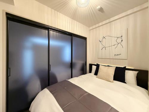 a bedroom with a large bed with black doors at Lifement - 1min to Peace Park, Modern and Secure Apt in Hiroshima