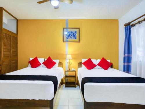 a bedroom with two beds with red pillows on them at Capital O Parador Crespo Hotel, Oaxaca in Oaxaca City
