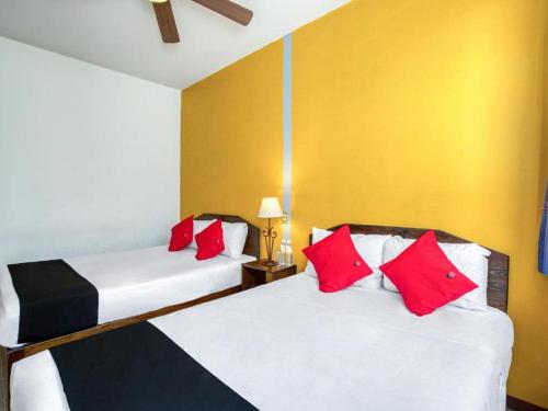 two beds in a room with red and white pillows at Capital O Parador Crespo Hotel, Oaxaca in Oaxaca City