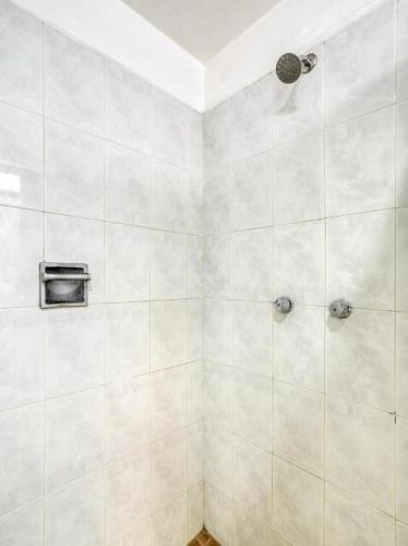 a bathroom with a shower with white tiles at Capital O Parador Crespo Hotel, Oaxaca in Oaxaca City