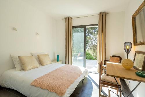 une chambre avec un lit, un bureau et une fenêtre dans l'établissement Belle villa 3 chambres au cœur du maquis, à Porto-Vecchio