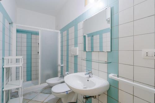 een badkamer met een wastafel, een toilet en een spiegel bij Villa Mery Villaggio Chiusurelle in Torre Lapillo