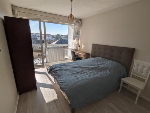 une chambre avec un lit, une chaise et une fenêtre dans l'établissement Ma Bourgogne grand 3 pièces avec balcons plein sud, parking interieur, à Dijon