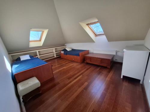 an attic room with two beds and wooden floors at Dom nad jeziorem na Kaszubach in Miszewko
