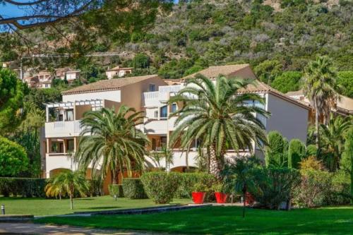 une grande maison blanche avec des palmiers en face d'une montagne dans l'établissement L’Anse de Pramousquier - Sea View and Leisure, au Lavandou