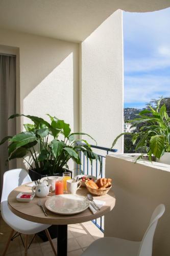 a table with a plate of food on a balcony at Hotel Amarante Cannes in Cannes