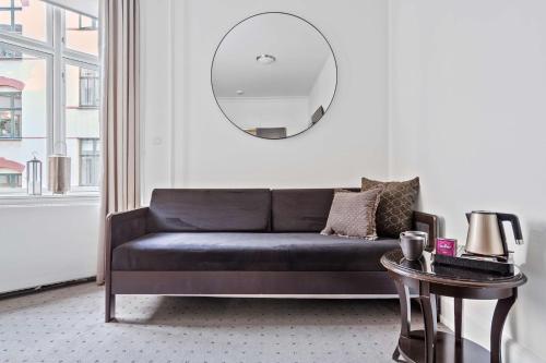 a black couch in a living room with a mirror at Best Western Hotel Hebron in Copenhagen