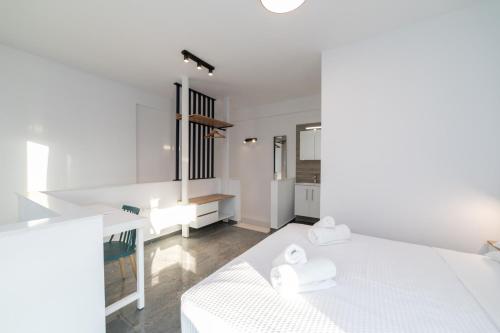 a white bedroom with a white bed and a kitchen at Nefeli & Nefeli Luxury Residential Complexes in Ofrínion