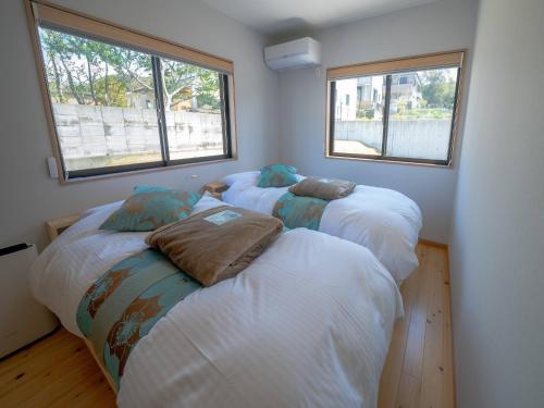 three beds in a room with two windows at OceanVilla Naruto in Naruto