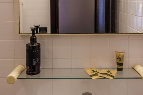 a bathroom with a bottle of soap and a mirror at Hotel alla Grotta in Lazise