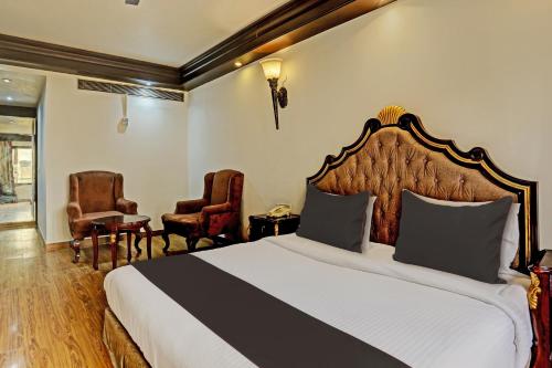a hotel room with a bed and two chairs at Super Townhouse The Royce New Friends Colony in New Delhi