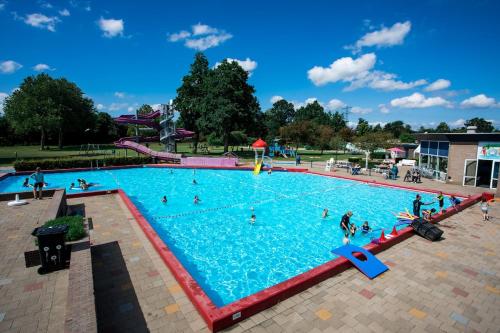 a large swimming pool with people in the water at Chalet met privé tuin & hottub Zeeland VP064 in Heinkensand