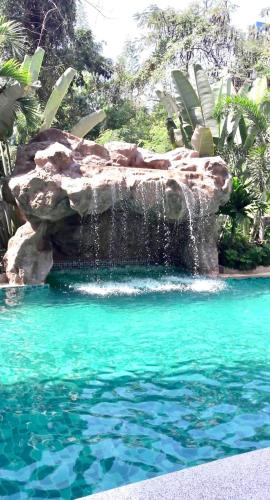 a swimming pool with a waterfall and blue water at Club Royal Apartments in North Pattaya