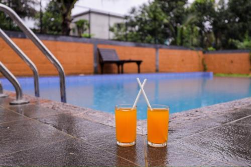 two glasses of orange juice sitting on a table near a swimming pool at sky blue villa in Vythiri