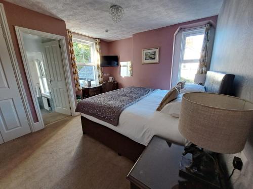 a bedroom with a large bed in a room with pink walls at Fern Howe Guest House in Keswick