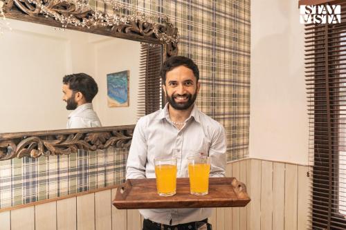 a man holding a tray with a tray of orange juice at StayVista at The Apricot with Heater & BBQ in Mashobra