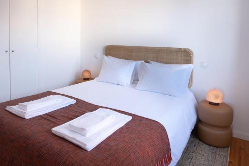 a bedroom with a bed with two white towels on it at Riverfront Stylish Apartment - waterfront 2BR in Viana do Castelo
