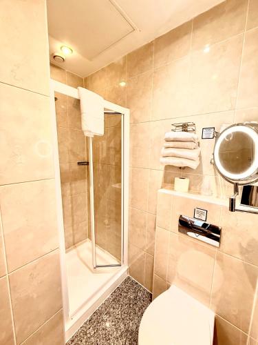 a bathroom with a shower and a toilet and towels at Best Western Corona Hotel in London