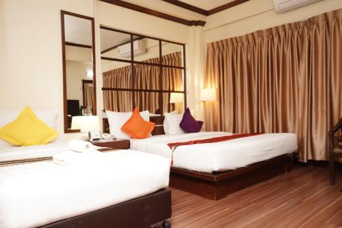 a hotel room with two beds and a mirror at Grand Business Inn in Bangkok