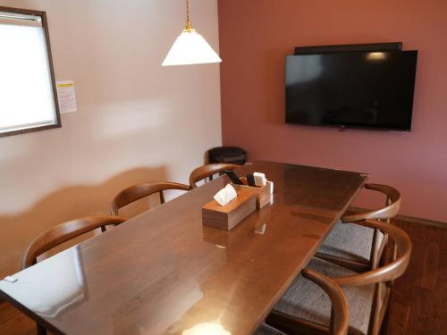 a dining room table with chairs and a flat screen tv at Enishiya Izumo in Taisha
