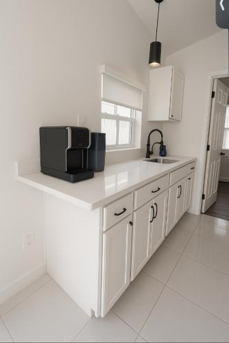 a white kitchen with a sink and a microwave at Modern Home - Termpurpedic Queen bed, Laundry, Free Parkging, EV Tesla in Hollywood
