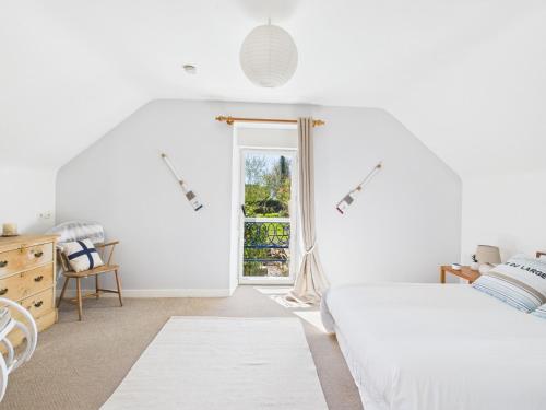 ein weißes Schlafzimmer mit einem Bett und einem Fenster in der Unterkunft -Fisher- Maison lovee au port de Kerdruc in Névez