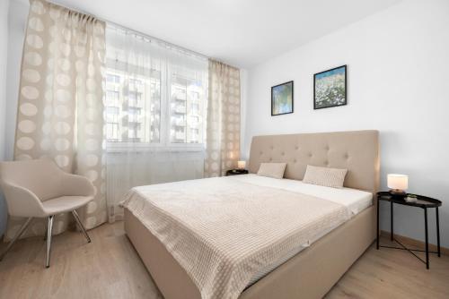 ein Schlafzimmer mit einem Bett und einem Stuhl und einem Fenster in der Unterkunft Brand New, Cozy Free parking apartment in Bratislava