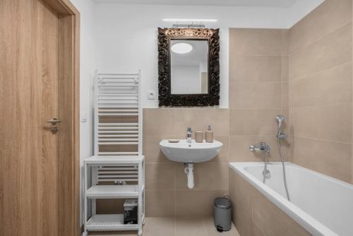ein Badezimmer mit Waschbecken, Badewanne und Spiegel in der Unterkunft Brand New, Cozy Free parking apartment in Bratislava
